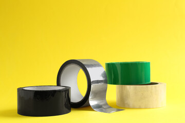 Rolls of different adhesive tapes on yellow background
