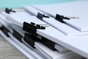 Binder clips with sheets of paper on table, closeup
