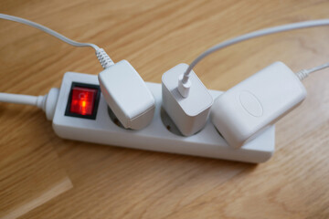 Three electric cables are plugged into a power strip socket extension cord