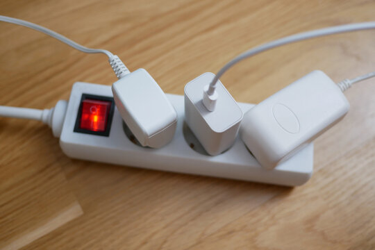 Three electric cables are plugged into a power strip socket extension cord