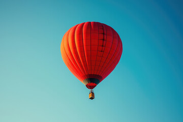 Fototapeta premium A vibrant red hot air balloon ascends against a clear, azure sky.