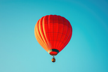 Fototapeta premium A vibrant red hot air balloon ascends against a clear blue sky, a breathtaking sight of adventure and freedom.