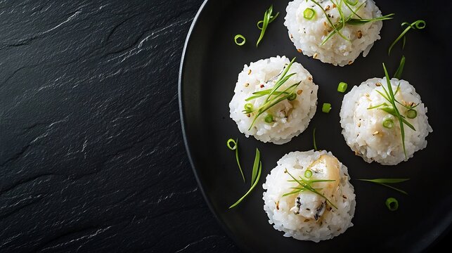 Top down view of Japanese tai meshi steamed rice sea bream garnished with green onions served on a black background
