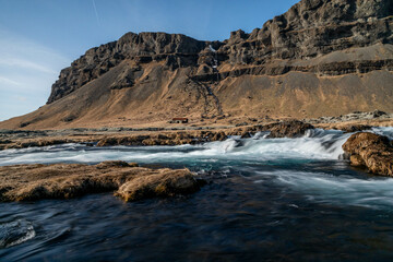 a small river in the south of Iceland with an old barn in the background