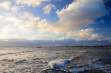 Ocean with Dramatic Sky, City Skyline, and Lone Boat