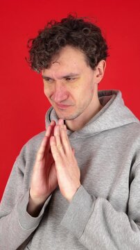 Mysterious sly curly man steeple fingers and schemes something tries to made up mind makes devious tricky plan isolated red background, studio shot. Evil genius action. Guy have idea. Planning evil.