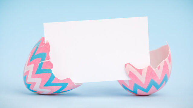 Pink and blue painted Easter egg broken apart space for text. Decorated Easter egg cracked open with blank greeting card for text.