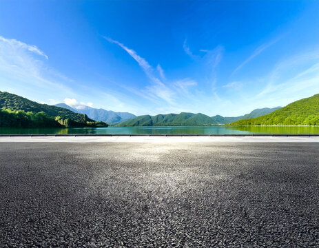 Asphalt road square and clear lake with green mountain nature landscape under blue sky. Car background.