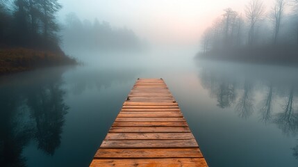 Obraz premium Misty Morning at the Lake: A Serene Wooden Dock Extends into the Fog-Shrouded Waters, Reflecting the Tranquil Atmosphere of Nature.