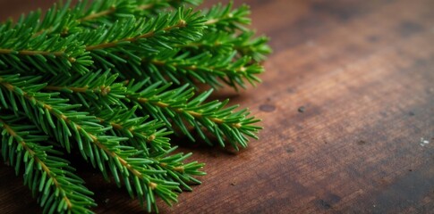 Naklejka premium Freshly cut evergreen branches on wooden table, fresh evergreen, christmas branches, rustic christmas