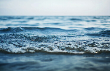 Fototapeta premium Close up view of gentle waves lapping on the shore under a soft overcast sky at the ocean horizon
