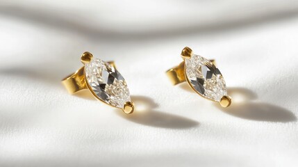Marquise-cut diamond earrings with a delicate gold setting, placed on a plain white backdrop