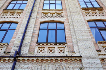Obraz premium Brick classic facade of 19 century building with large windows. Old building with downspout in Kyiv, Ukraine