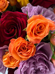 Beautiful bouquet of vibrant roses shades of orange, red, and purple. Flowers artistically arranged, with delicate petals. Naturally organic plants, perfect for holiday designs, top view