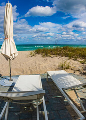 Two white sunbeds and a closed umbrella, Golden beach, Miami, USA