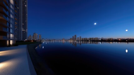 Fototapeta premium Modern urban waterfront at night. A tranquil scene of city buildings reflecting on calm water. A paved walkway leads to a body of water, with illuminated lighting accents
