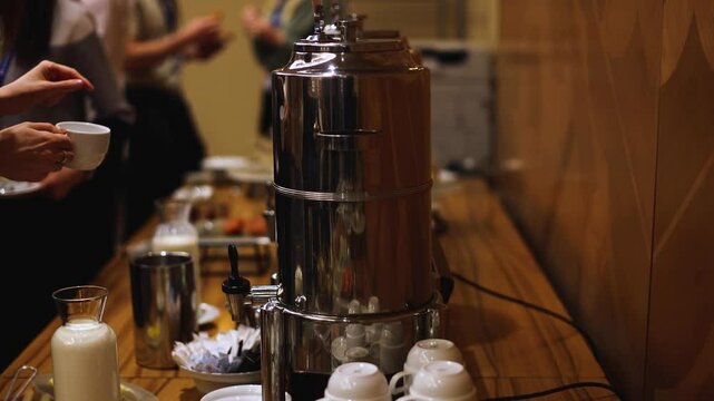 Set of coffee break lunch in the hotel restaurant during conference meeting, with tea and coffee catering, decorated banquet table with white tableware and metal tea maker machine boiler
