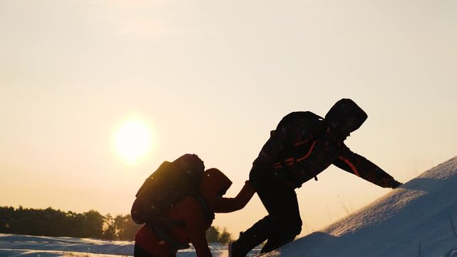 climbers climb snowy mountain sunset winter. teamwork concept. overcoming obstacles together. give helping hand. business teamwork silhouette. hiking path mountains. success active sports backpacks