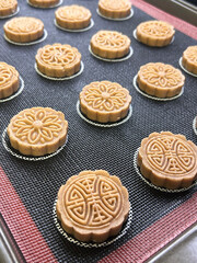 Traditional Mooncakes Arranged Neatly on a Baking Tray Ready for Baking in a Cozy Kitchen