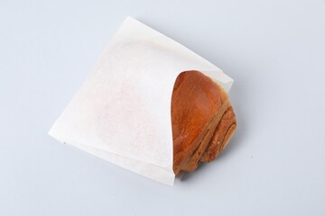 Paper bag with freshly baked bun on white background, above view