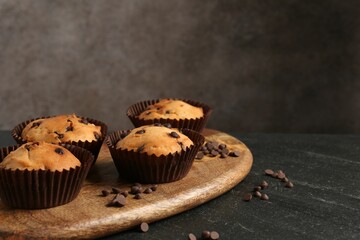 Delicious muffin with chocolate chips on black table, closeup. Space for text