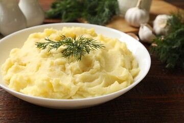 Delicious mashed potato with dill served on wooden table, closeup