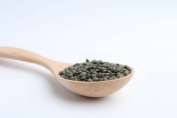 Raw lentils in wooden spoon isolated on white