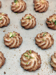 Swirl cookies made from rich dough and topped with nuts are laid out on a baking sheet, ready for cooling and serving