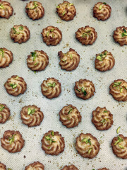 Swirl cookies made from rich dough and topped with nuts are laid out on a baking sheet, ready for cooling and serving