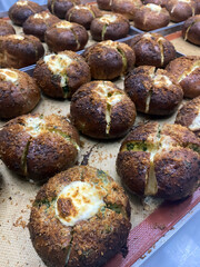 Freshly baked rolls with a golden crust and melted cheese are cooling in a lively bakery kitchen, filling the air with a delightful aroma
