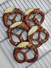 Warm, soft pretzels with a glossy finish rest on a wire cooling rack in a charming bakery just after baking