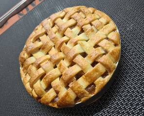 A freshly baked lattice pie sits on a textured surface, highlighting its golden-brown crust and...