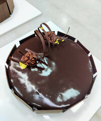 A beautifully crafted chocolate cake adorned with chocolate curls and gold accents sits enticingly...