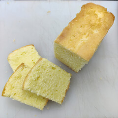Soft, moist slices of pound cake are arranged neatly next to a whole cake, showcasing their texture and color in the bakery