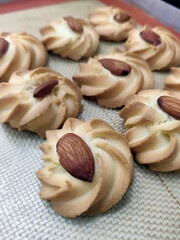 Freshly baked almond cookies are beautifully arranged in a bakery, showcasing their golden color and nutty topping, perfect for dessert lovers