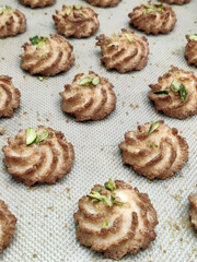 Swirl cookies made from rich dough and topped with nuts are laid out on a baking sheet, ready for...