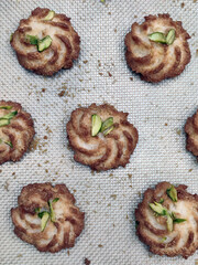 Swirl cookies made from rich dough and topped with nuts are laid out on a baking sheet, ready for...