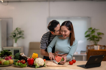 A man and a woman are kissing while cutting a watermelon