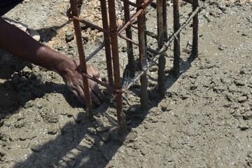 Worker Adjusting Steel Reinforcement in Wet Concrete