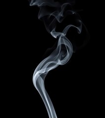 Wispy tendrils of gray smoke curl and dissipate against a stark black backdrop, isolated, photography
