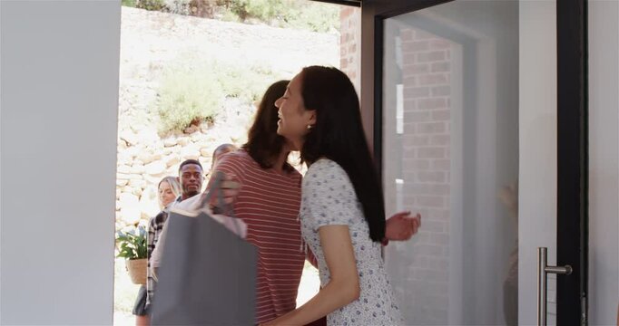 Group of happy diverse friends entering house and giving presents at a house-warming party