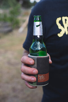 Anonymous man holding beer bottle outdoors in backyard