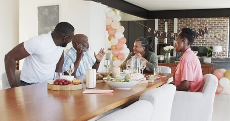 Happy black couple and senior parents making a toast at retirement party in living room