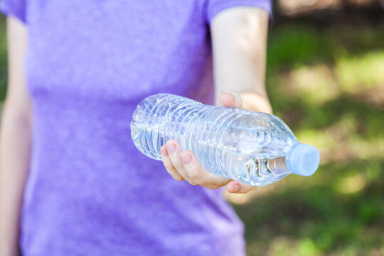 Person holding out plastic water bottle with water in it