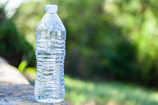 Close up of plastic water bottle outside with green bokeh background