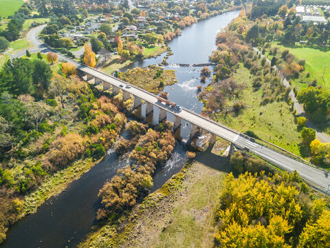 Aerial view of a truck crossing a bridge leading into a riverside country town