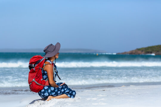 Backpacker with rucksack sitting on white sand beach