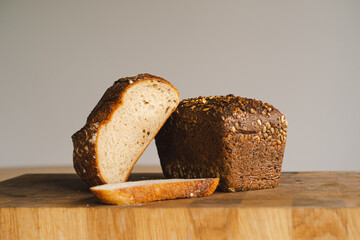 Sourdough bread, freshly baked and still warm, are stacked on a wooden surface. The bread are...