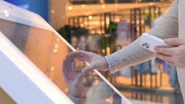 Person is touching a screen with a cell phone in their hand. Concept of technology and the role it plays in our daily lives - Powered by Adobe