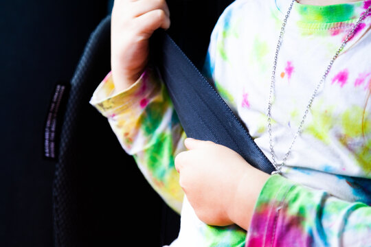 Little girl happily wearing seat belt in booster seat in car